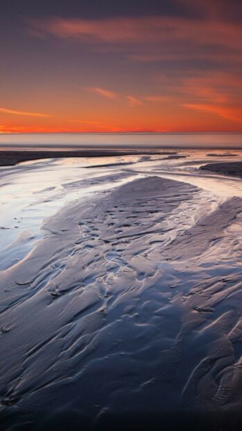 Sunset reflecting on the wet sand at the beach with National Geographic patterns