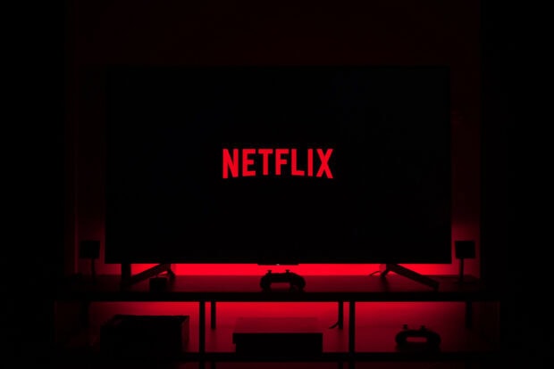 A dark room with a large screen displaying the Netflix logo illuminated by red light