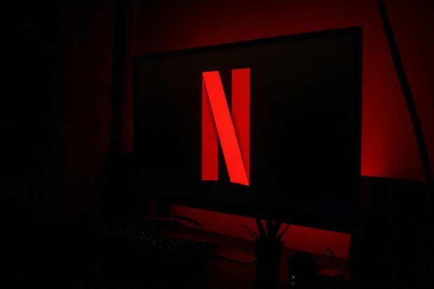 Red Netflix logo displayed on a computer monitor in a dark room with ambient lighting