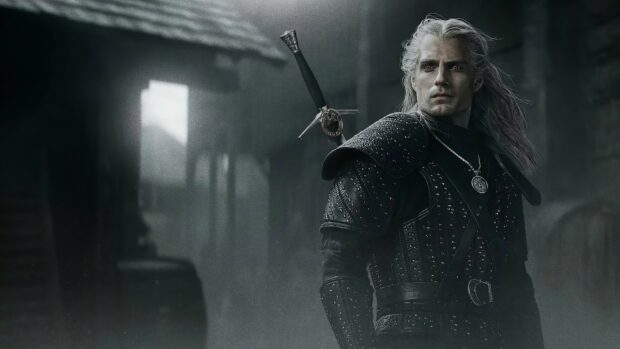 A warrior with white hair and black armor stands with a sword on his back in a dark misty setting