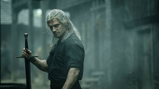 Geralt of Rivia from the Netflix series standing with a sword in a dark misty environment