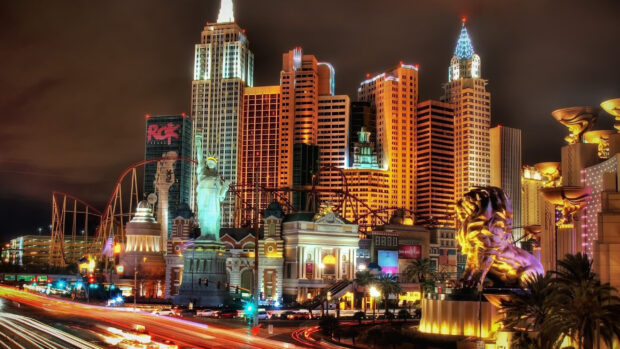 Illuminated city buildings and statue in Nevada skyline at night with busy traffic trails