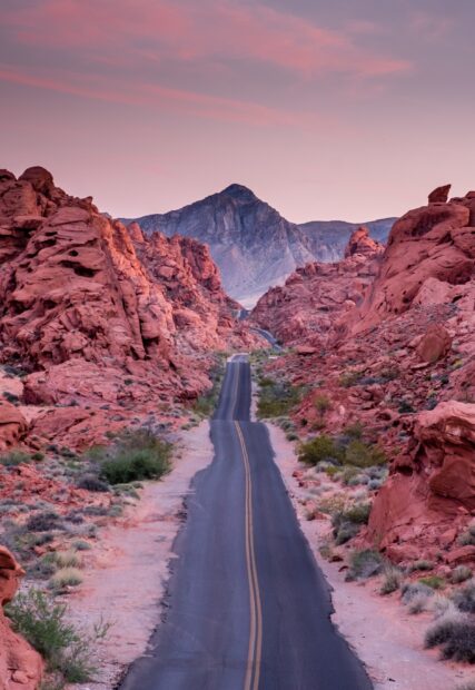 Scenic Nevada road surrounded by red rock formations at sunset