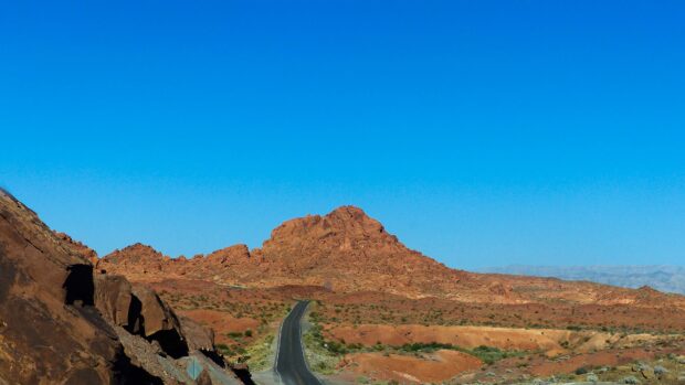 A winding road through Nevada desert rocky landscape under clear blue sky
