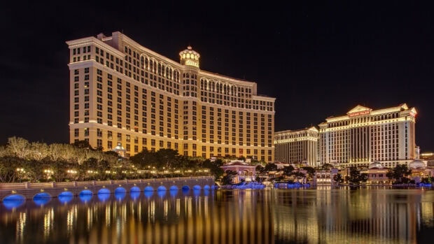Night view of Nevada cityscape with illuminated Bellagio and Caesars Palace buildings reflecting on water