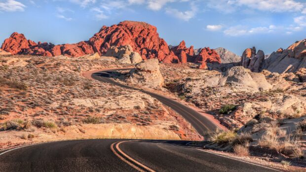 Winding road passing through Nevada red rock desert landscape with clear blue sky