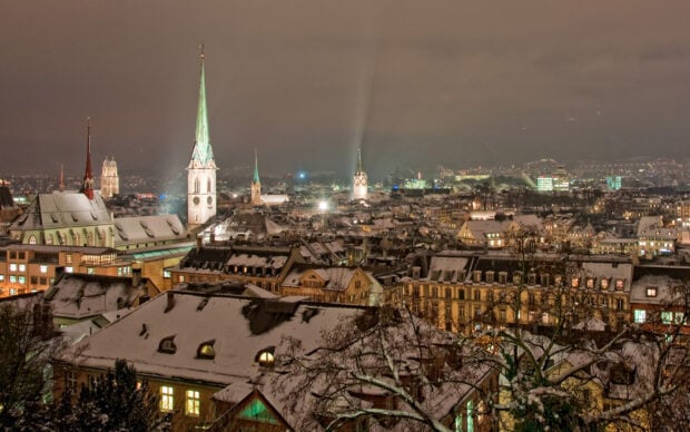 Snow covered rooftops and illuminated church spires in a cityscape at night in New Delhi