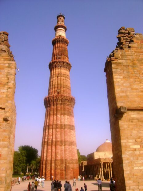 The Qutub Minar tower in New Delhi stands tall among historic ruins and visitors