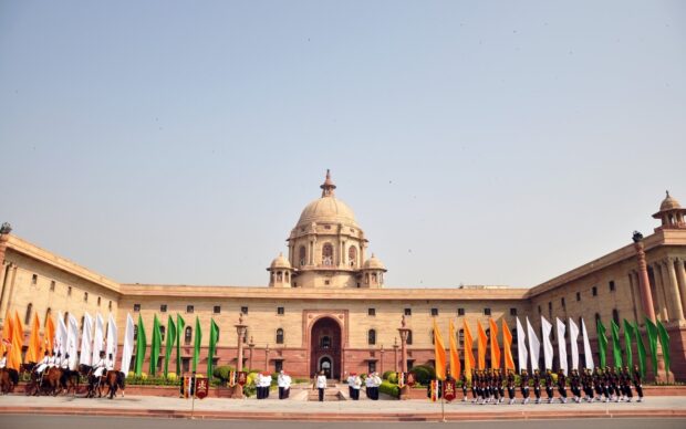 The historic government building is decorated with tricolor flags and soldiers in New Delhi