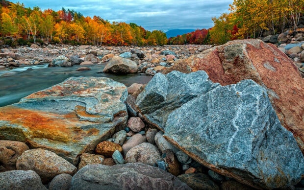 Colorful autumn forest and rocks along a river in New Hampshire