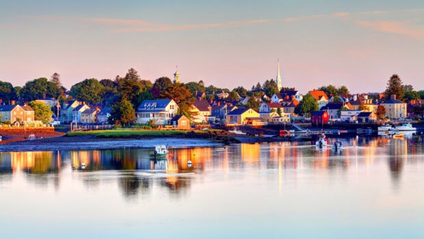 A peaceful New Hampshire coastal town reflecting colorful houses and boats at sunset