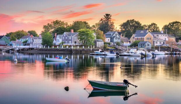 Quiet New Hampshire harbor with boats and houses under a colorful sunset sky