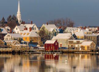 Snow covered houses in New Hampshire town with water reflections in winter