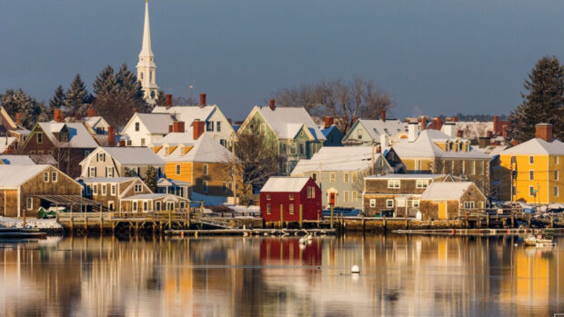 Snow covered houses in New Hampshire town with water reflections in winter