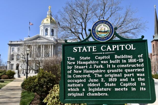 State Capitol building of New Hampshire with a historical sign in Concord