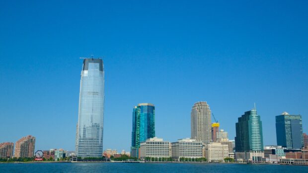 A clear view of New Jersey skyline with modern skyscrapers and calm waterfront under a blue sky
