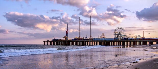 A scenic view of New Jersey pier with an amusement park against a colorful sky at sunset