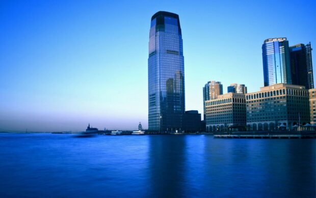 The New Jersey city skyline with a tall glass building reflecting the blue sky above the water