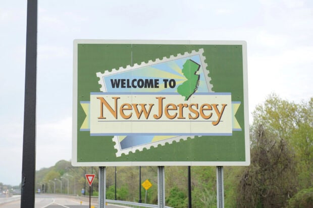 Welcome to New Jersey road sign showing the state shape and name on a highway