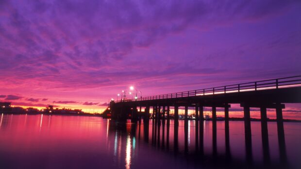New Jersey pier with vibrant purple sunset sky over calm water reflection