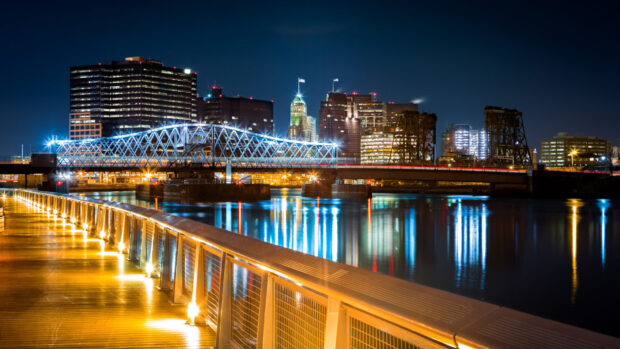 Night view of New Jersey cityscape with illuminated bridge and waterfront walkway