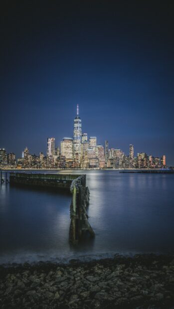 Nighttime view of New Jersey skyline with waterfront and pier in clear sky