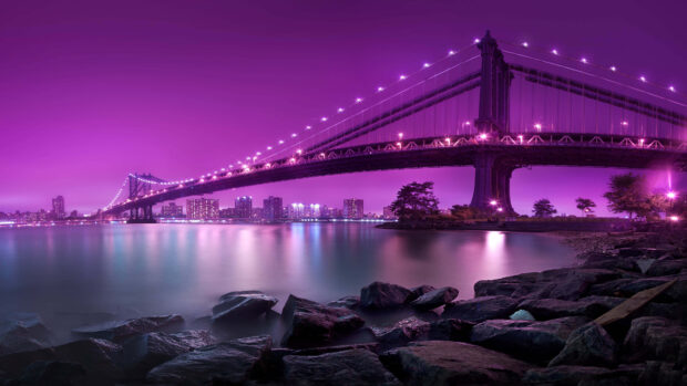 New York skyline at night with bridge and city lights reflecting on the water