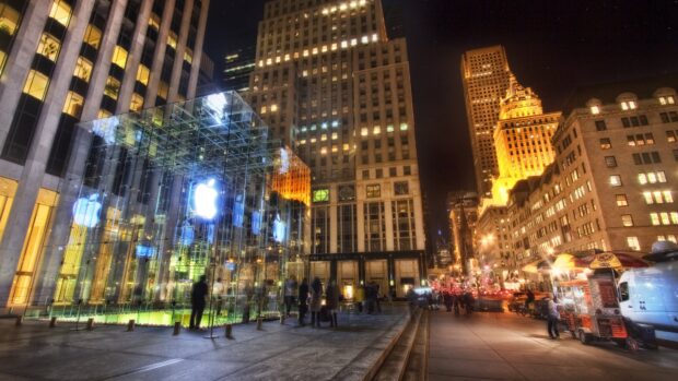 Night view of New York street with illuminated glass Apple store and tall buildings