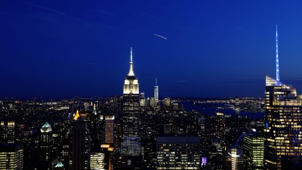 Nighttime cityscape of New York featuring iconic skyscrapers and bright lights
