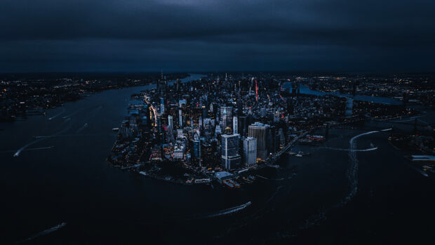 New York city skyline at night with illuminated buildings and waterways viewed from above