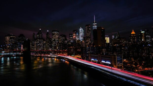 Nighttime view of New York skyline with vibrant city lights and busy highway