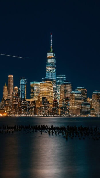 The vibrant New York cityscape at night with illuminated skyscrapers and calm water reflections
