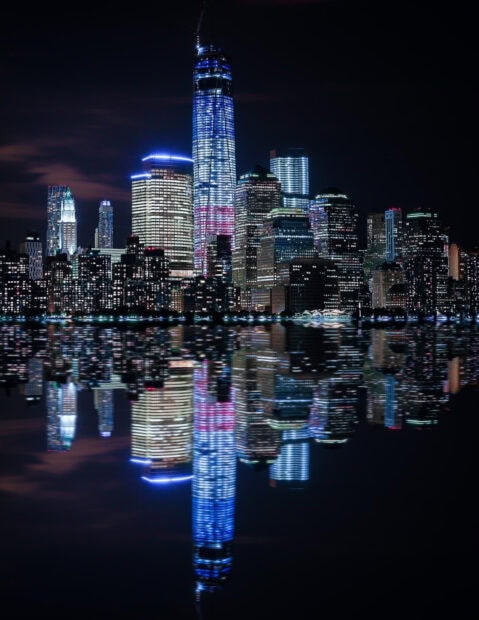 Stunning New York city skyline reflecting on water at night with vibrant lights and tall buildings