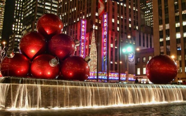 Giant red Christmas ornaments at Radio City with New York Christmas decorations at night