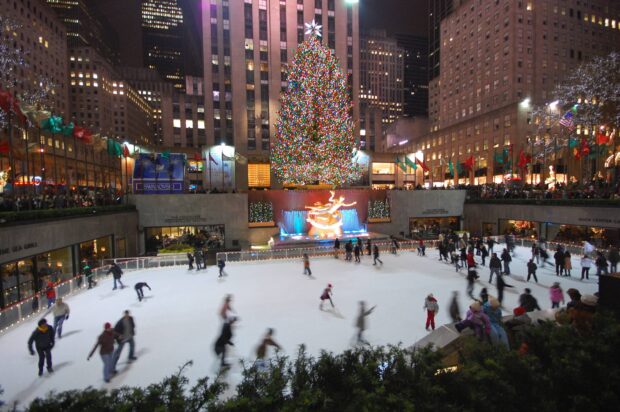 People ice skating under New York Christmas tree at Rockefeller Center on a winter night