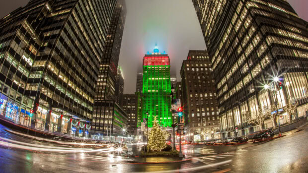 A New York Christmas scene with a tall building decorated in green and red lights on a rainy night