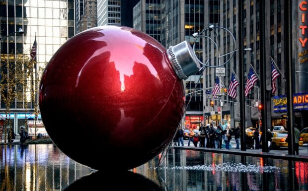 A giant New York Christmas ornament decoration in the city reflecting the urban scene