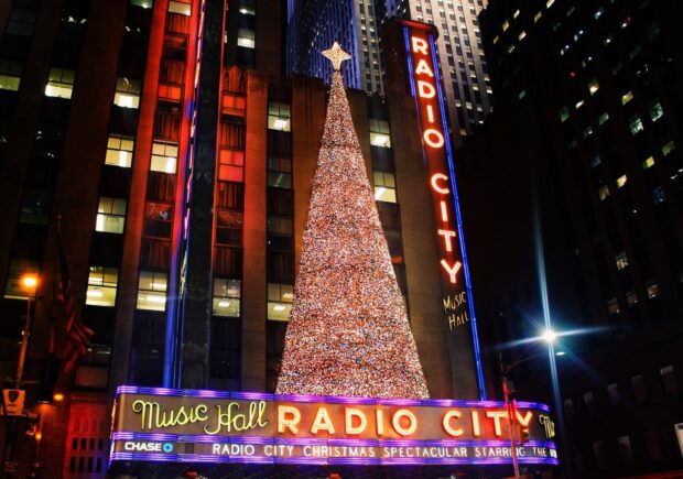 A large Christmas tree covered in lights in front of Radio City Music Hall in New York city