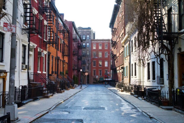A quiet city street in New York streets with classic brick buildings on both sides and fire escapes