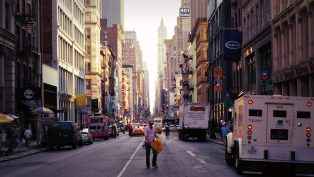 A person walking on a busy New York street surrounded by tall buildings and vehicles