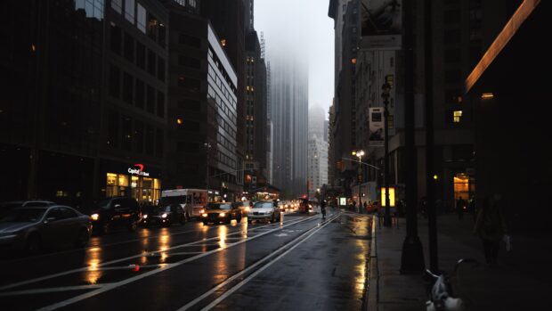 A rainy evening on New York streets with cars and tall buildings surrounded by mist