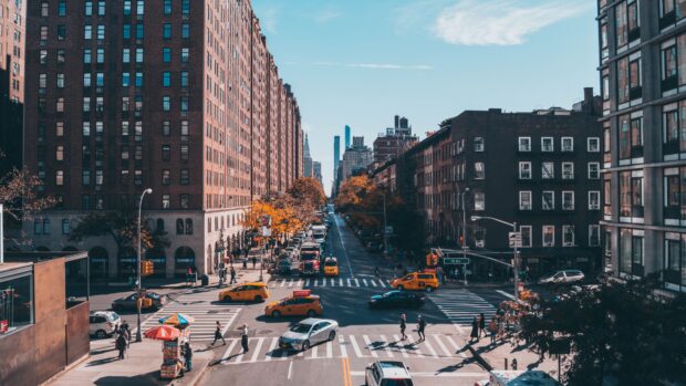 A busy New York Streets scene with tall buildings and yellow taxis crossing the intersection