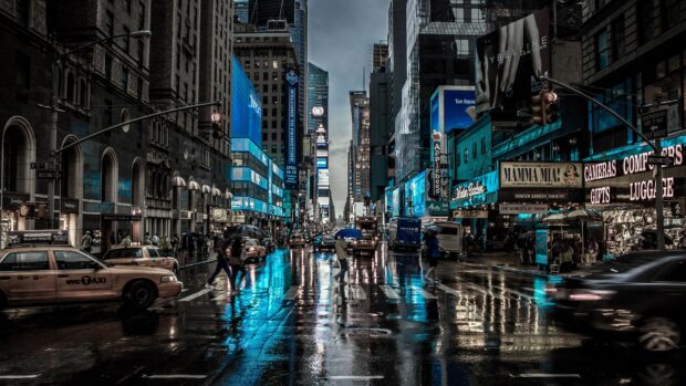 People crossing New York streets on a rainy day with bright city lights and taxi cars