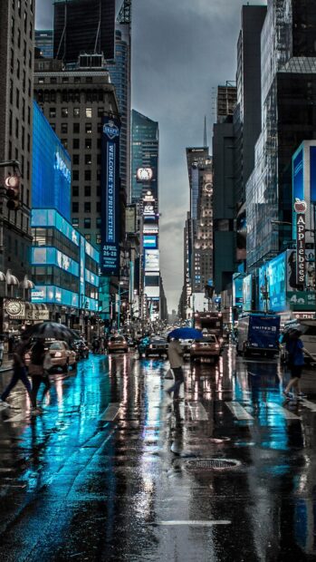 People walking with umbrellas on rainy New York streets reflecting city lights