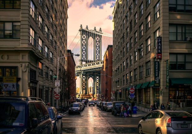 A New York street view with traffic and the Manhattan bridge in the background at sunset