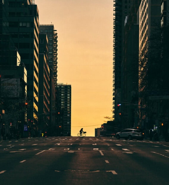 A cyclist riding through quiet New York streets during sunset in a cityscape