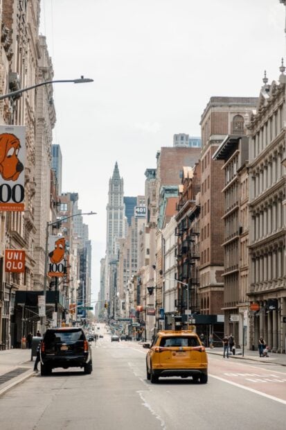 A busy New York streets scene with tall buildings and yellow taxi in clear daylight