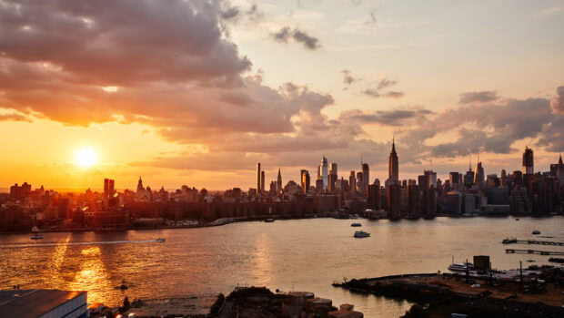 New York city skyline at sunset with vibrant clouds and river reflections showcasing a beautiful New York Sunset