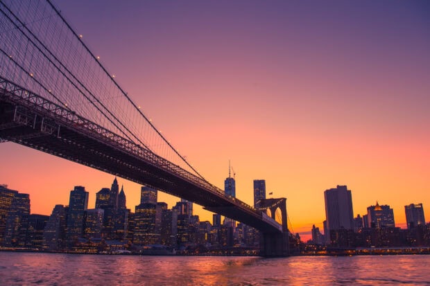 New York cityscape with a vibrant sunset sky featuring the iconic Brooklyn Bridge