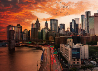 A vibrant New York skyline with sunset clouds and city traffic during golden hour